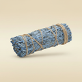 Blauwe salie smudge stick gebundeld met jute touw op warme beige achtergrond, mat oppervlak met zachte slagschaduw