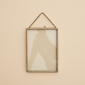 Hangende fotolijst verouderd messing 13x18 cm op warme beige achtergrond, studiofoto