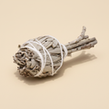 Witte salie smudge stick gebundeld met witte draad op warme beige achtergrond, mat oppervlak met zachte slagschaduw