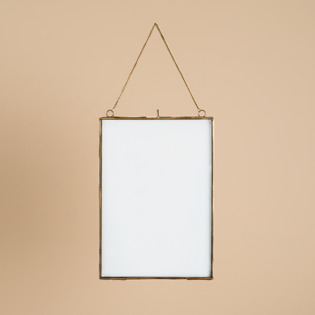 Hangende fotolijst antiek messing 21x29,5 cm op warme beige achtergrond, studiofoto