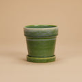 Groene bloempot met schotel, diameter 13 cm, op warme beige achtergrond, studiofoto