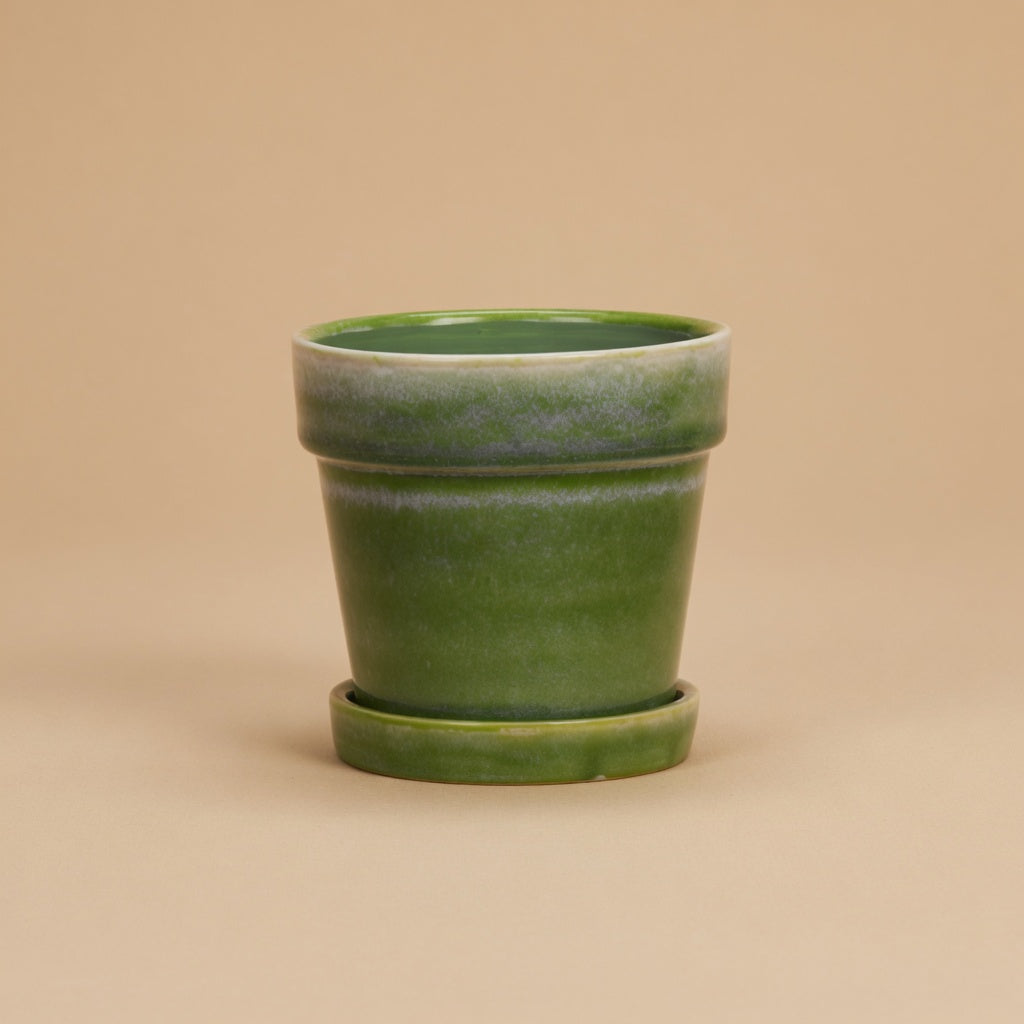 Groene bloempot met schotel, diameter 13 cm, op warme beige achtergrond, studiofoto
