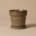 Beige bloempot met schotel, diameter 13 cm, op warme beige achtergrond, studiofoto