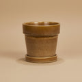 Mosterdgele bloempot met schotel, diameter 13 cm, op warme beige achtergrond, studiofoto