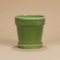 Groene bloempot met schotel, diameter 18 cm, op warme beige achtergrond, studiofoto