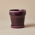 Paarse bloempot met schotel, diameter 18 cm, op warme beige achtergrond, studiofoto