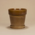 Mosterdgele bloempot met schotel, diameter 18 cm, op warme beige achtergrond, studiofoto